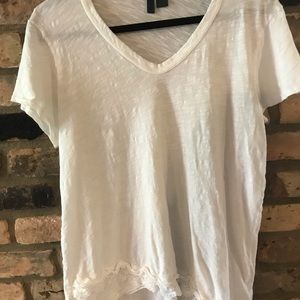 L left of center white short tshirt with detail.